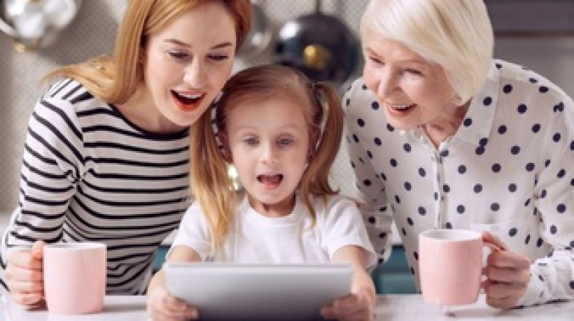 exciting-cartoon-pleasant-little-girl-watching-a-cartoon-on-tablet-together-with-her-grandmother-and-mother-drinking-coffee-from-pink-mugs-while-looking-amused-by-plot-twists_259150-25392